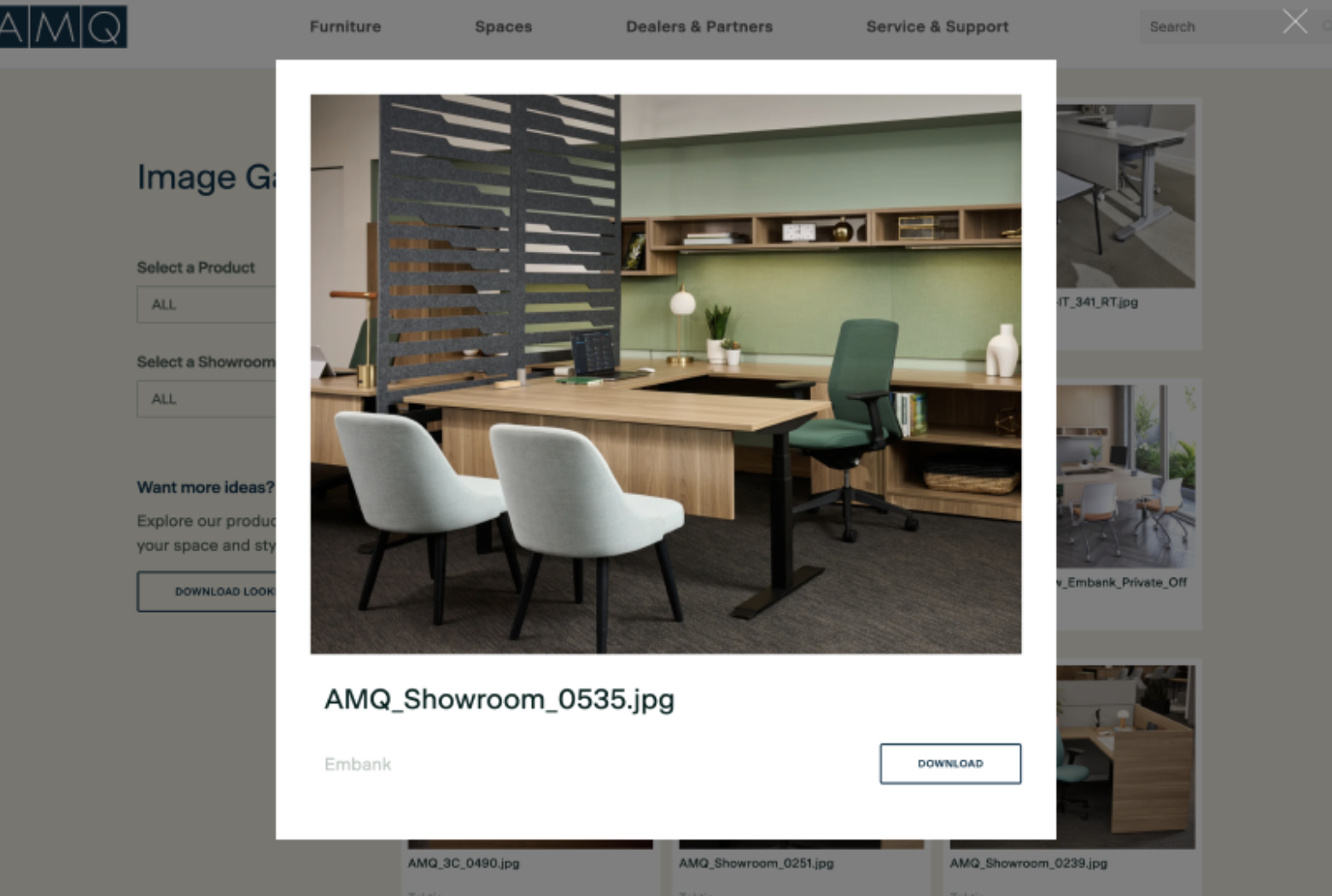 Wooden L-shaped office desk with green ergonomic chair and light gray guest chairs in a showroom with a slatted divider.